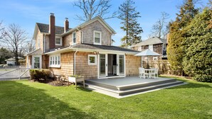 A two-story house with a covered patio and a well-maintained lawn.