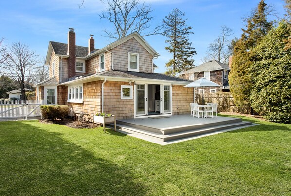 A two-story house with a covered patio and a well-maintained lawn.