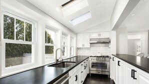 A modern kitchen with white cabinets, a black countertop, and stainless steel appliances.