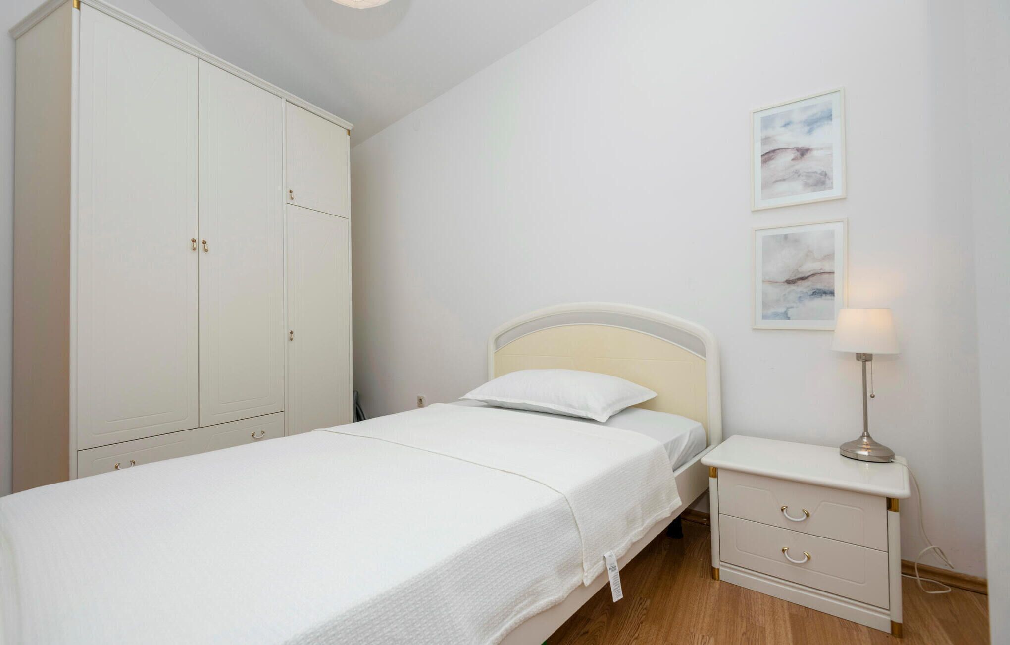 A bedroom with a bed, a nightstand, a lamp, and a wardrobe.