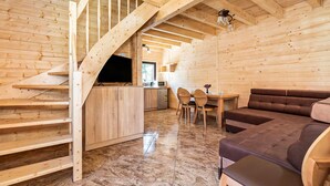 Ein Holzinnenraum mit Treppe, einer Küchenzeile und einer Sitzecke inklusive Sofa und Sesseln.