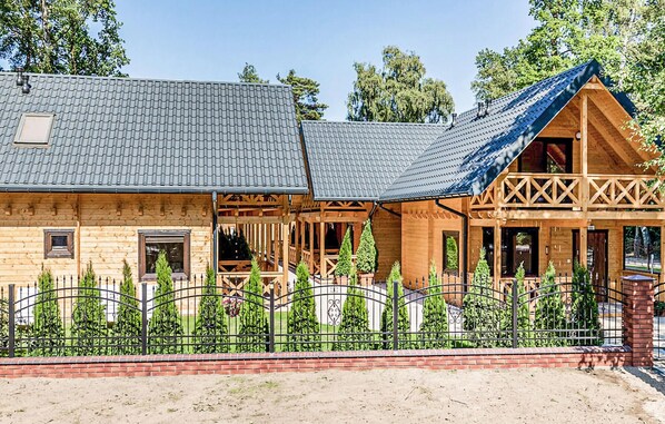 A wooden cabin with a sloped roof, a covered porch, and a fenced garden area.