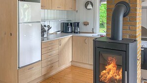 Een keuken met houten kastjes, een ingebouwde kookplaat met vlammen en een koffiezetapparaat op het aanrecht.