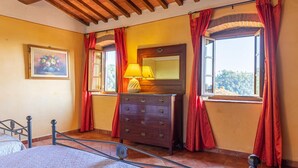 Una habitación con cama, cómoda, lámpara y un cuadro en la pared.