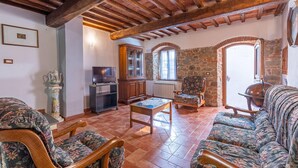 Un salón acogedor con mobiliario de madera, televisión y una pared de piedra.