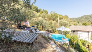 Entorno rústico al aire libre con una terraza de madera, una piscina pequeña y un jardín.