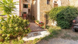 Un estrecho callejón con edificios de piedra, una escalera y plantas en macetas.