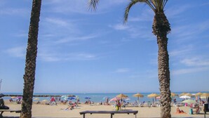 Une plage bordée de palmiers, avec des parasols et des gens qui se détendent.