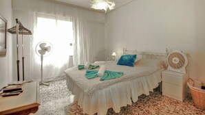 Une chambre à coucher avec un lit, une table de chevet, une lampe et un ventilateur.