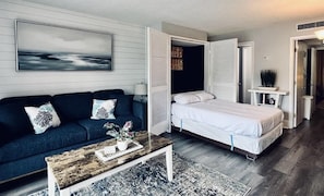 Een kamer met een bed, een bank, een salontafel en een schilderij aan de muur.