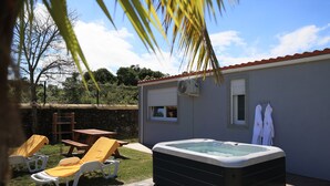 A backyard with a hot tub, lounge chairs, and a small table. - Parrots Village (Ribeira Grande)