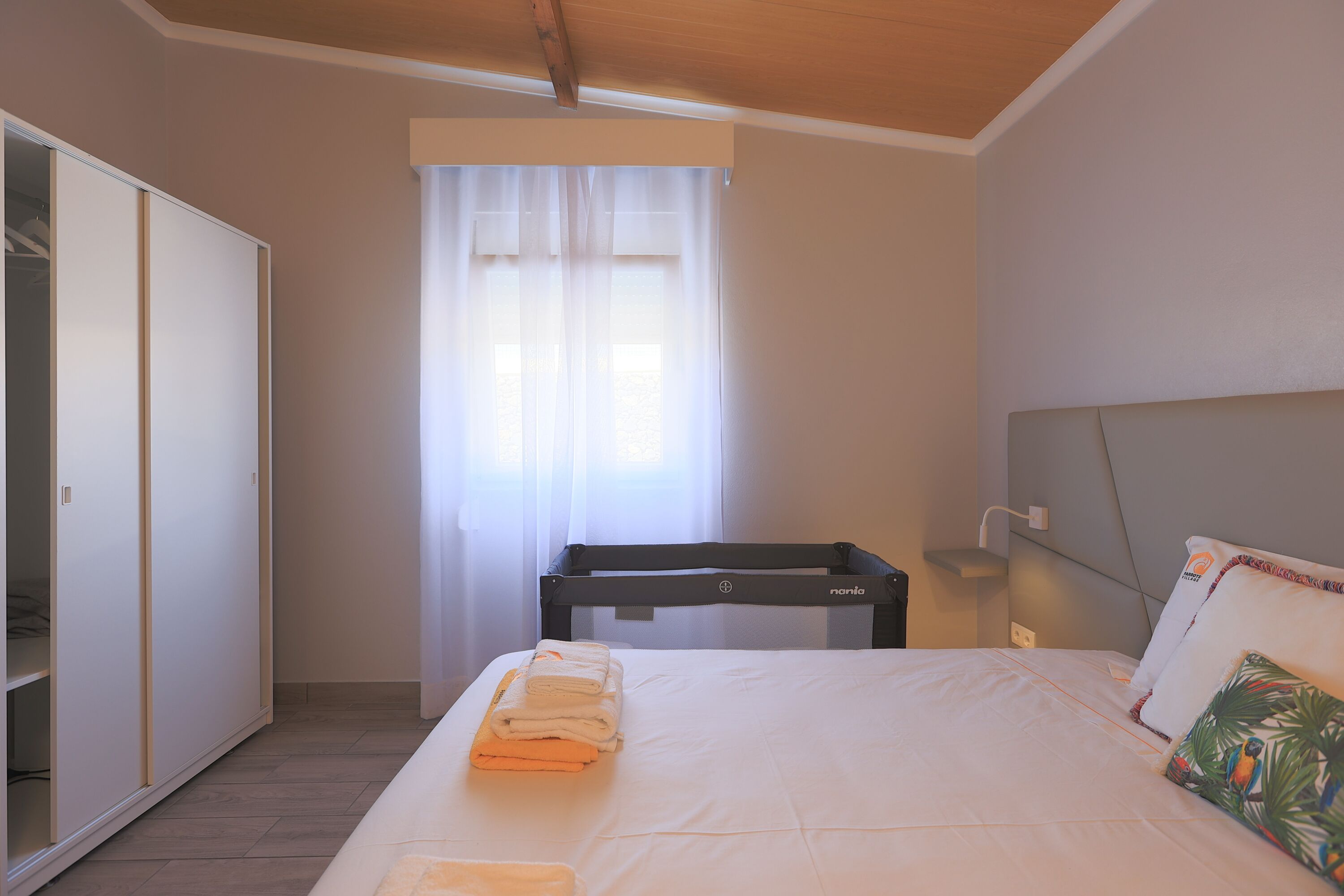Ein Schlafzimmer mit einem Bett, einem Kleiderschrank, einem Fenster mit Vorhängen und einem Nachttisch.