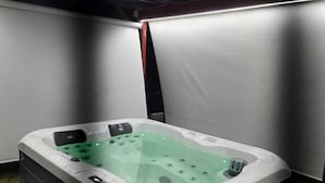 A hot tub in a basement with a concrete floor and metal beams. - Parrots Village (Ribeira Grande)