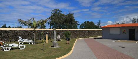 A paved walkway with a curved path, a stone wall, and a building with a red roof.