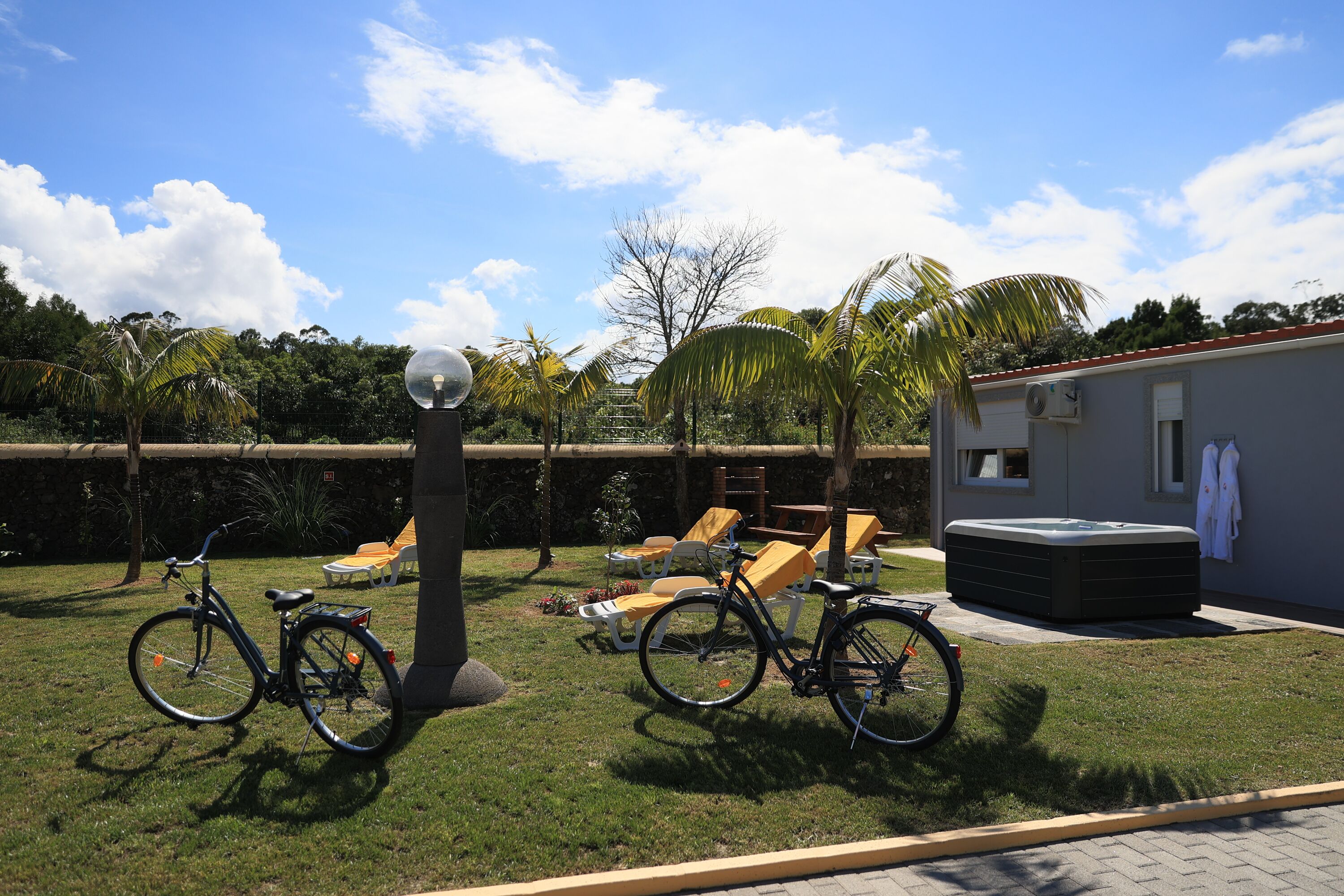 A backyard with a hot tub, lounge chairs, and bicycles.