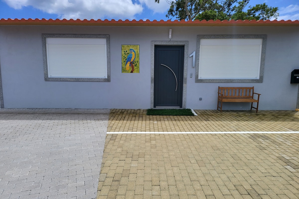 A building with two closed shutters, a door with a curved handle, a bench, and a small green mat at the entrance.