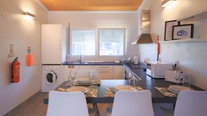 A modern kitchen with a dining area set for a meal. - Parrots Village (Ribeira Grande)