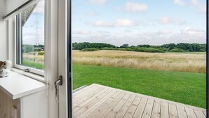 Een kamer met een groot raam met uitzicht op een grasveld en bomen.