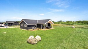 Een modern huis met twee verdiepingen, een overdekte patio en een gazon.
