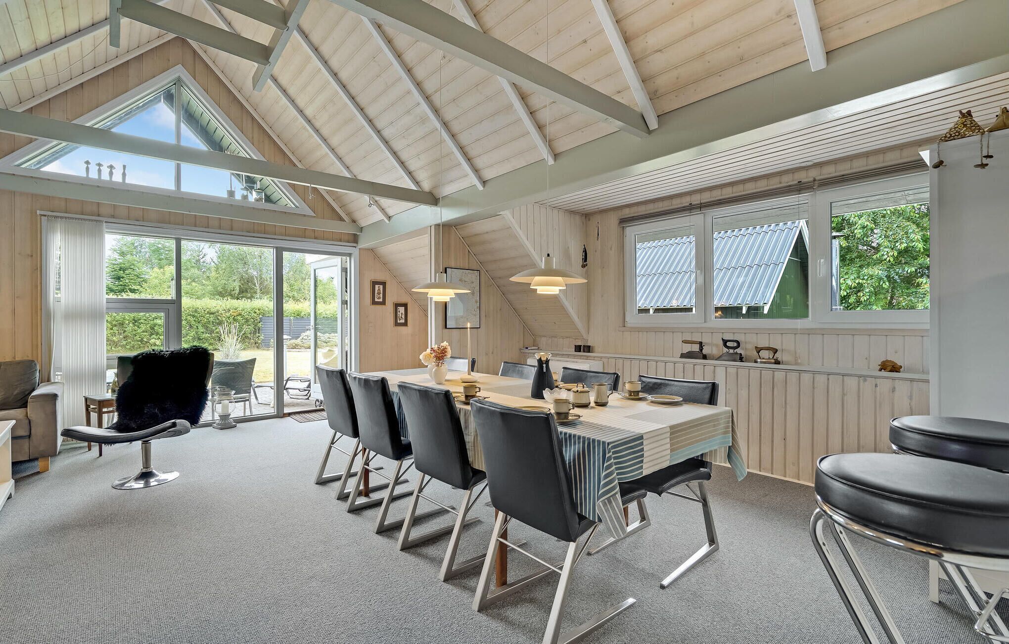 A spacious dining area with a high ceiling and large windows, providing ample natural light and views of the outdoors.