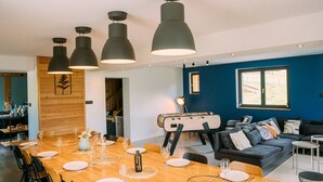 A modern dining area with a long wooden table set for six, black chairs, and pendant lighting. - CHALET DE LA FOUGERE 15 PERS 180M2 BAUGES (Thoiry)