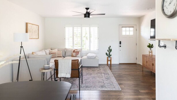 Een moderne woonkamer met een bank, salontafel en een eethoek met tafel en stoelen.