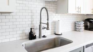 Een keuken met een RVS-spoelbak, een flexibele kraan, een zeepdispenser en een koffieapparaat.