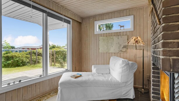 Ein gemütliches Zimmer mit einem weißen Sofa, einem großen Fenster, einer Karte an der Wand und einem Kamin.