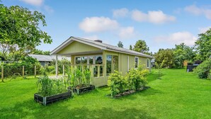 Einbungalow mit grüner Fassade und einer Veranda.