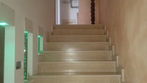 A staircase with a handrail, leading to a landing with a wall-mounted air conditioning unit and a vase with red flowers. - Business and vacation in an 'oasis of peace!!! (Valdarenne)