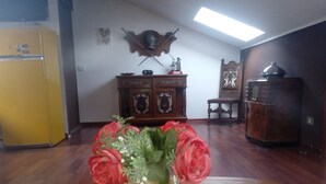 A room with a wooden floor, a yellow refrigerator, a wooden cabinet with decorative items, and a vase with red flowers on a table. - Business and vacation in an 'oasis of peace!!! (Valdarenne)