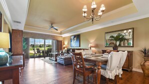 A spacious dining area with a chandelier, wooden dining table, and chairs.