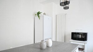 Una cocina con refrigerador, microondas, dos jarrones decorativos y una planta colgante.