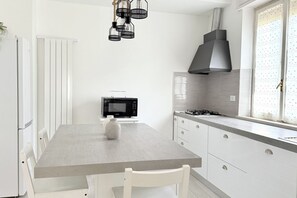 A modern kitchen with white cabinetry, a grey countertop, a black microwave, and a gas stove.