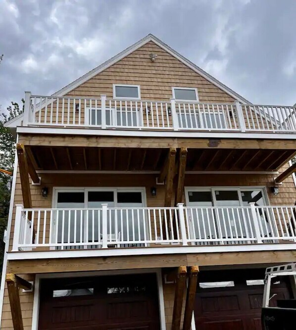 A two-story building with a balcony on the upper floor and a garage on the lower floor.