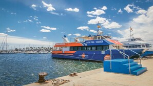 Un barco grande atracado en un puerto deportivo, con cielos despejados y aguas tranquilas.
