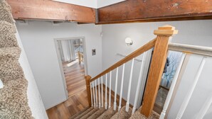 A staircase with wooden handrails and white balusters, leading to a room with a wooden floor and a door. - Game Cabin with 5 PM Late Checkout (Big Bear)