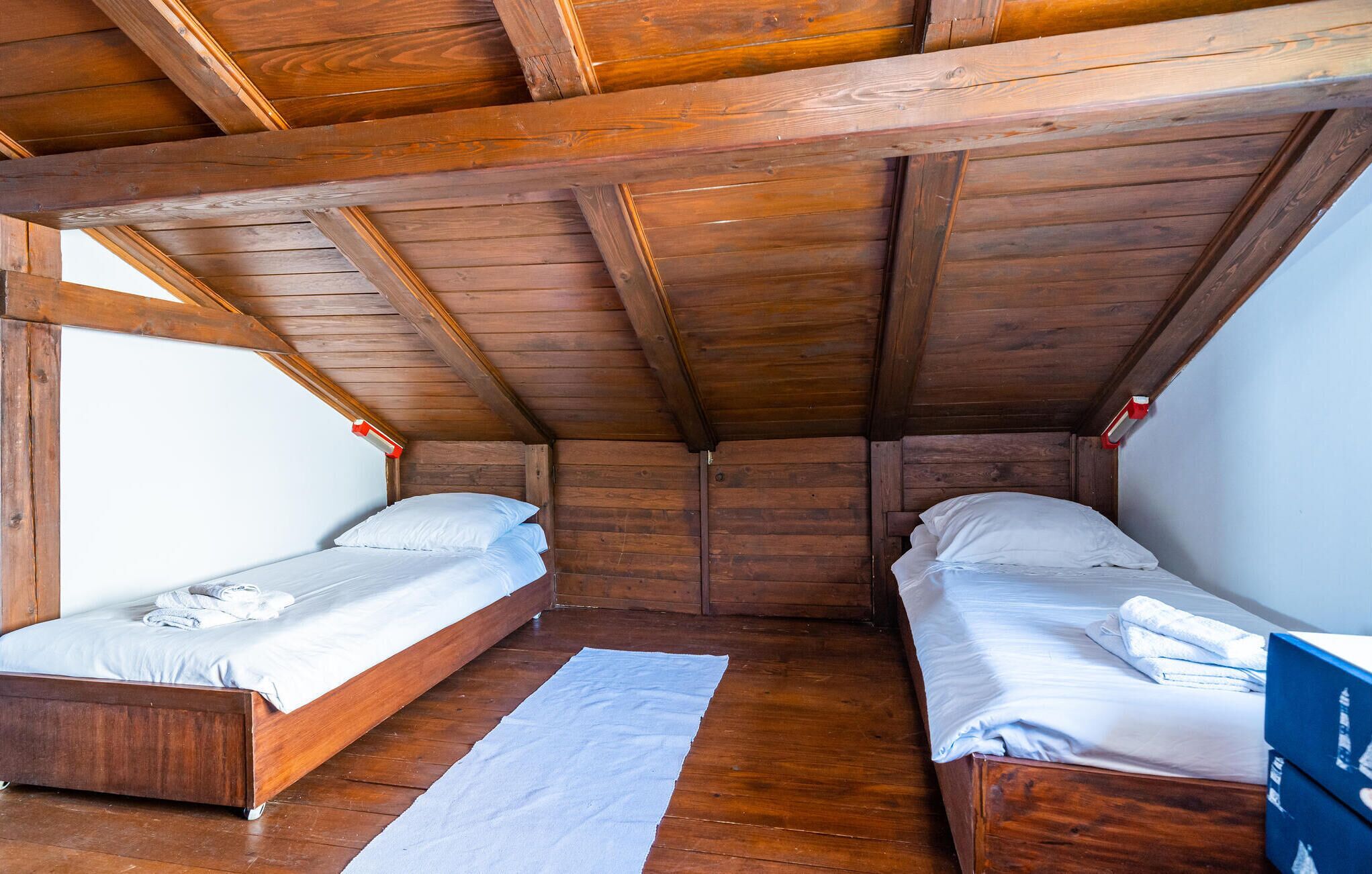 A cabin with two wooden bunk beds, a white rug, and a wooden ceiling.