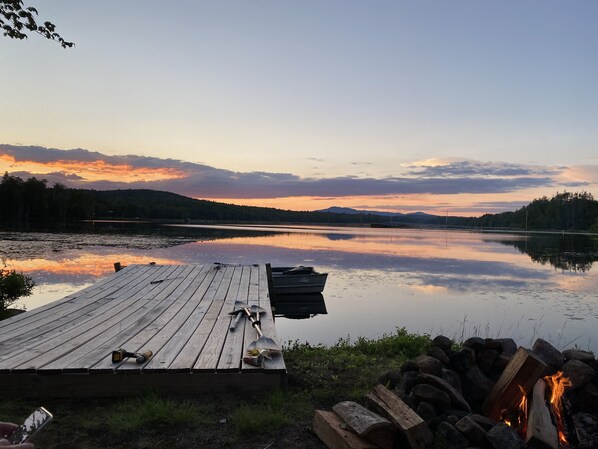 A wooden dock extending into a calm lake with a sunset in the background.