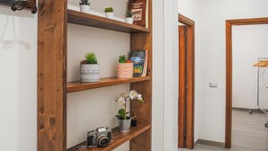 A hallway with wooden shelves holding plants, a book, and a camera.