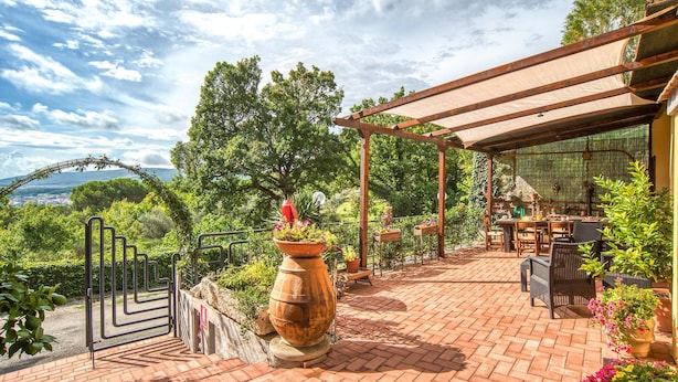 A patio with a pergola, outdoor seating, and a large planter.