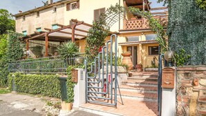 A residential property with a gated entrance, a wooden pergola, and a brick staircase leading to a door.