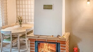 Una habitación acogedora con chimenea, una mesa de comedor con sillas y un jarrón con flores.