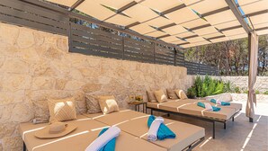 A sunlit outdoor lounge area with stone walls and a pergola providing shade. - 3 bedroom gorgeous home in Jadrtovac (Jadrtovac)