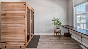 A room with a wooden cabinet, a potted plant, a window, and a view of the outside. - Spacious Home w/ Sauna & Fenced Yard w/ BBQ, Pet-Friendly, Sleeps 10, King Beds (Calgary)