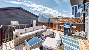 A covered outdoor patio with wicker furniture, a grill, and a view of the sky. - Spacious Home w/ Sauna & Fenced Yard w/ BBQ, Pet-Friendly, Sleeps 10, King Beds (Calgary)