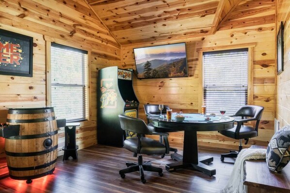 A cozy cabin with wooden walls and a dining area featuring a table, chairs, and a barrel.