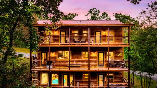 Una cabaña de madera de varios niveles con balcones, mobiliario exterior y una piscina.