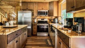 Cocina compacta con armarios de madera, electrodomésticos de acero inoxidable y encimera de granito.