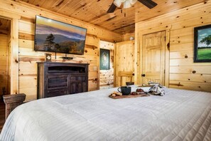 A wooden cabin room with a bed, a television on a wooden cabinet, and a door with a window.